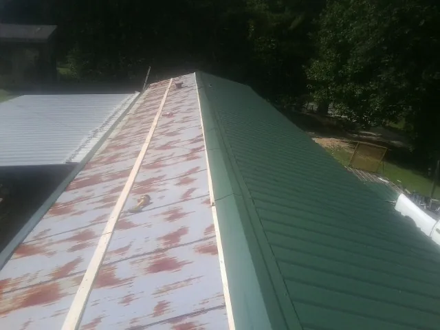 Old rusted panels beside newly installed green metal roofing — Wind Damage Roof Repair by Roofing Brothers in Beatty