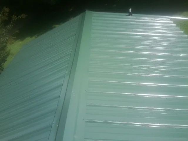 New green metal panels meeting at the ridge of a roof — Flat Roof Repair work by our crew in Beatty