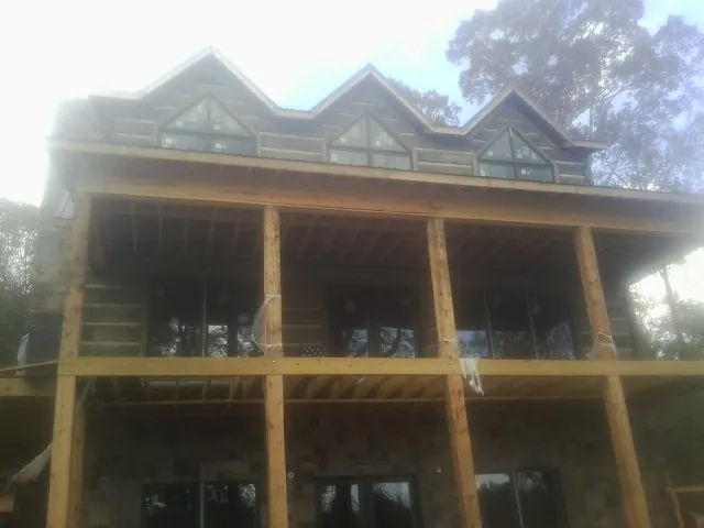 Dormers and porch framing on a large log home under construction — Roof Coating work by our crew in Beatty