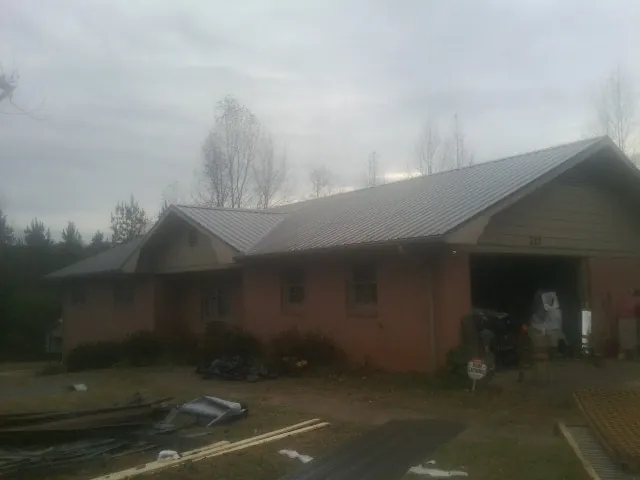 Gray metal roof on a stucco house with an attached garage in Beatty