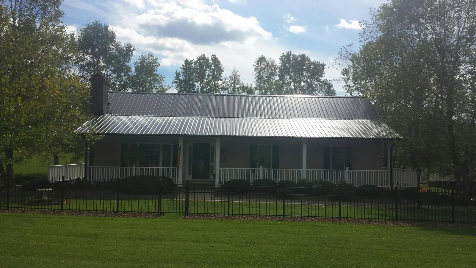 Gray metal roof on a brick ranch with a full width front porch — Gutter Guard Installation work by our crew in Beatty