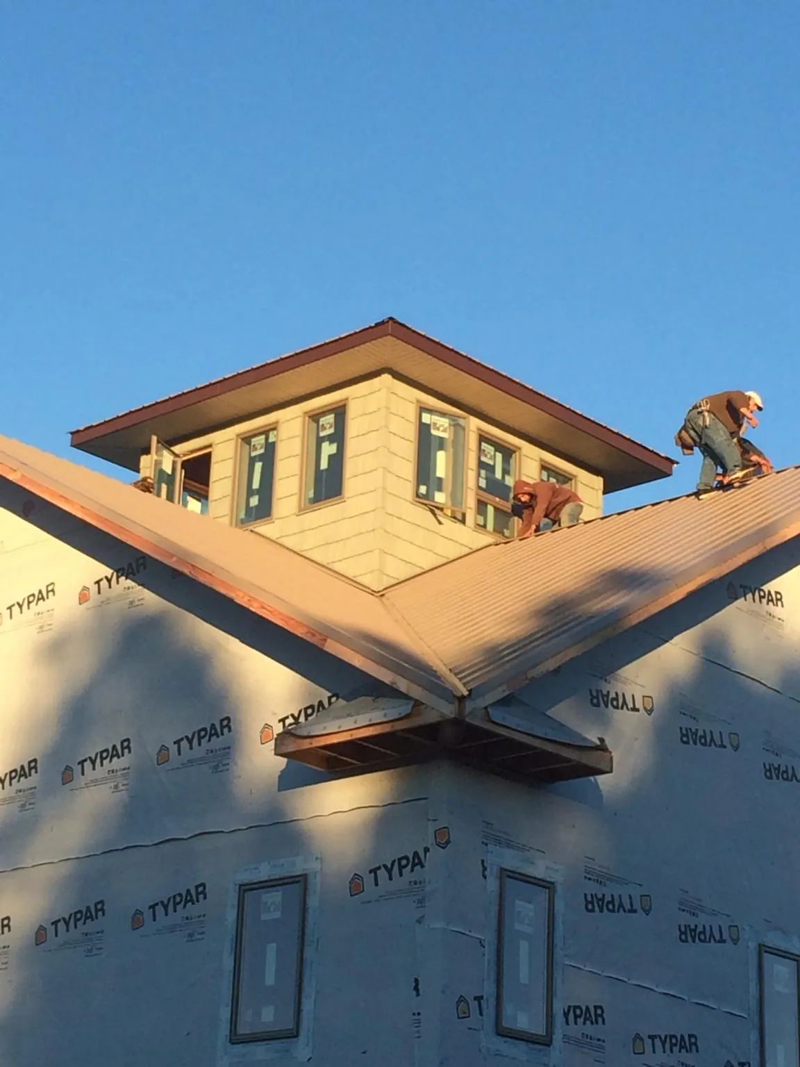 Roofers working around a rooftop cupola on a new metal roof at sunset — Roof Waterproofing in Beatty by Roofing Brothers